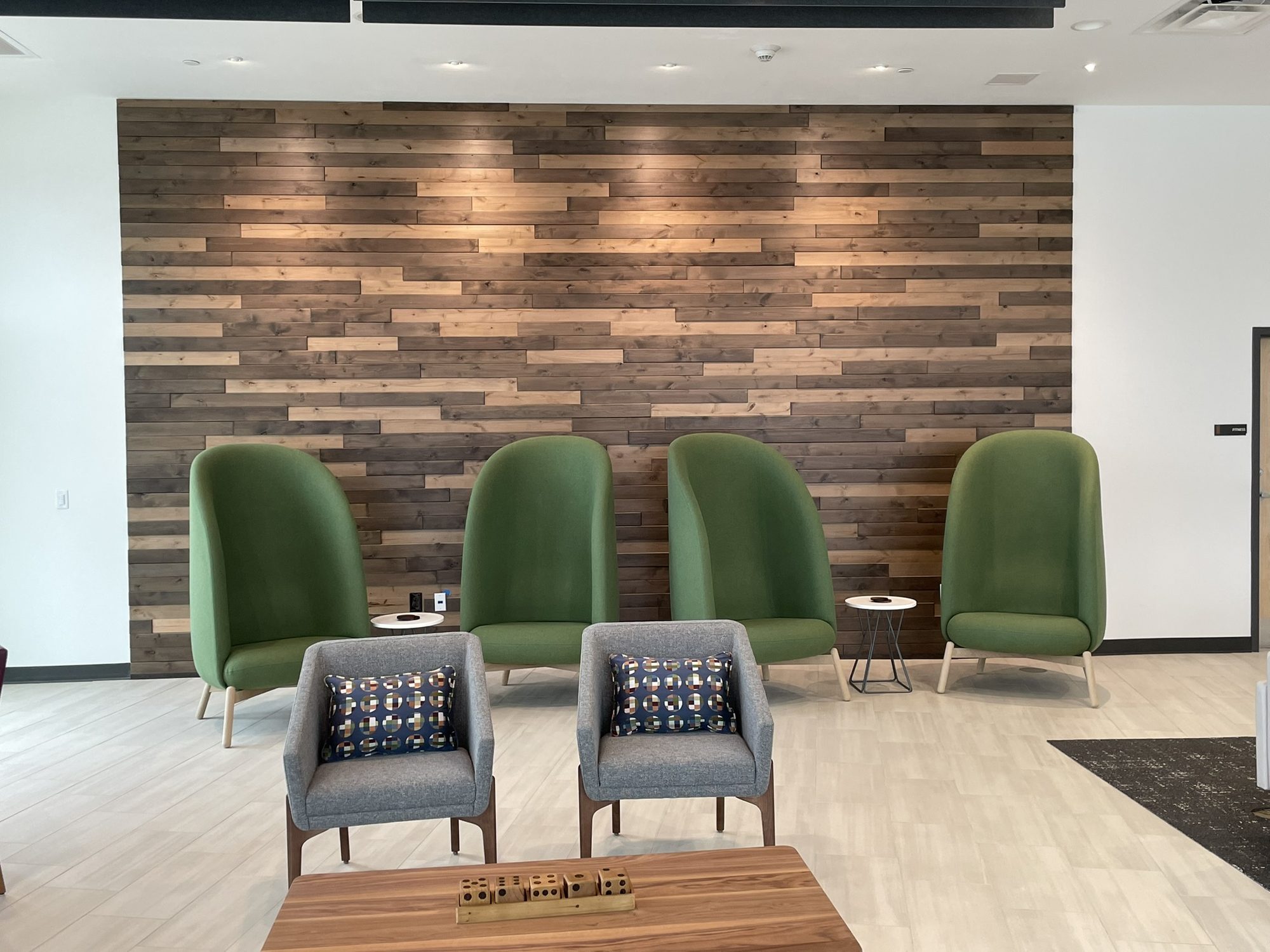 Lounge seating area in front of a floor-to-ceiling stained wood plank feature wall