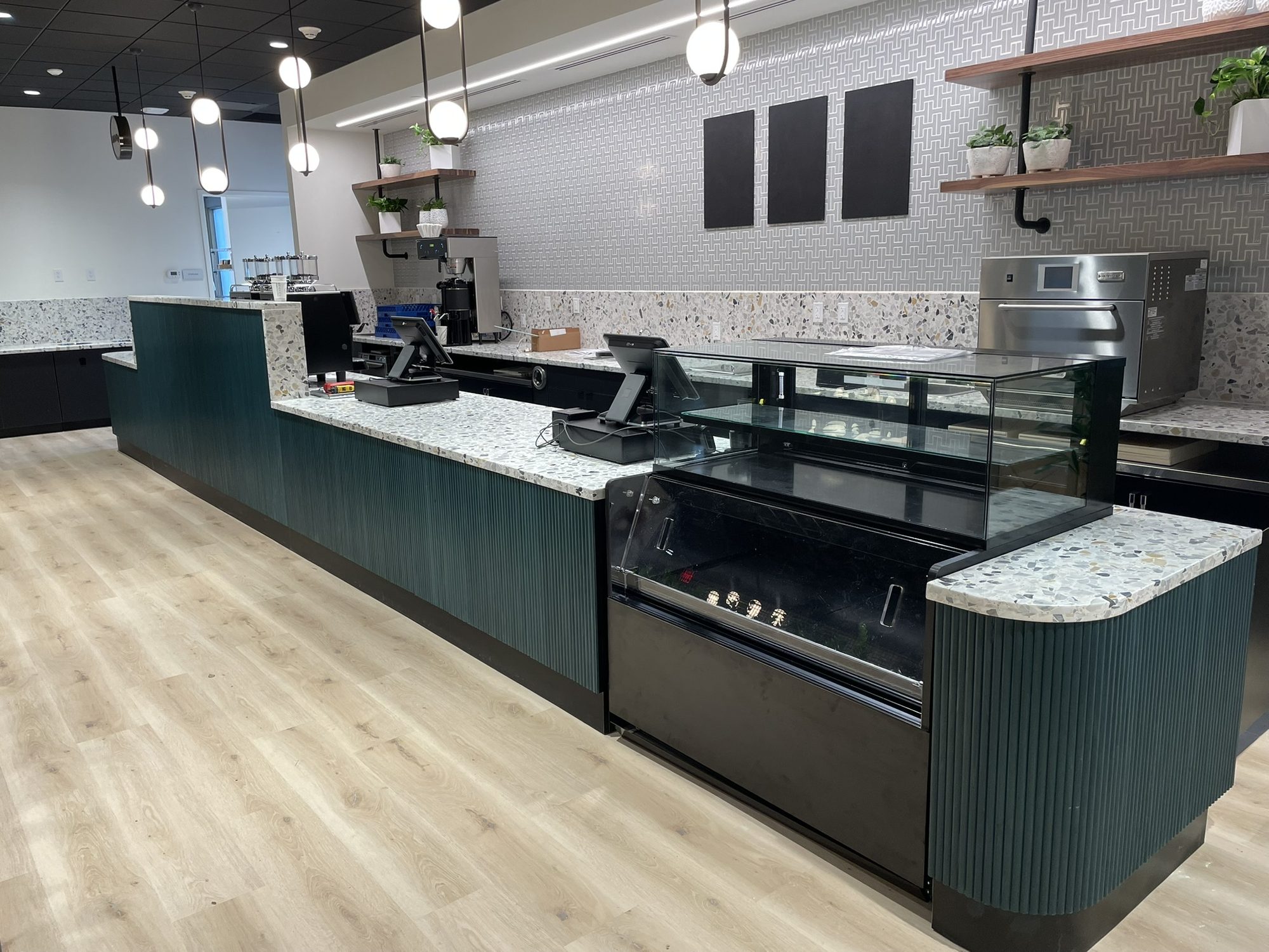 Café servery with dark green reeded cabinet fronts and terrazzo countertops