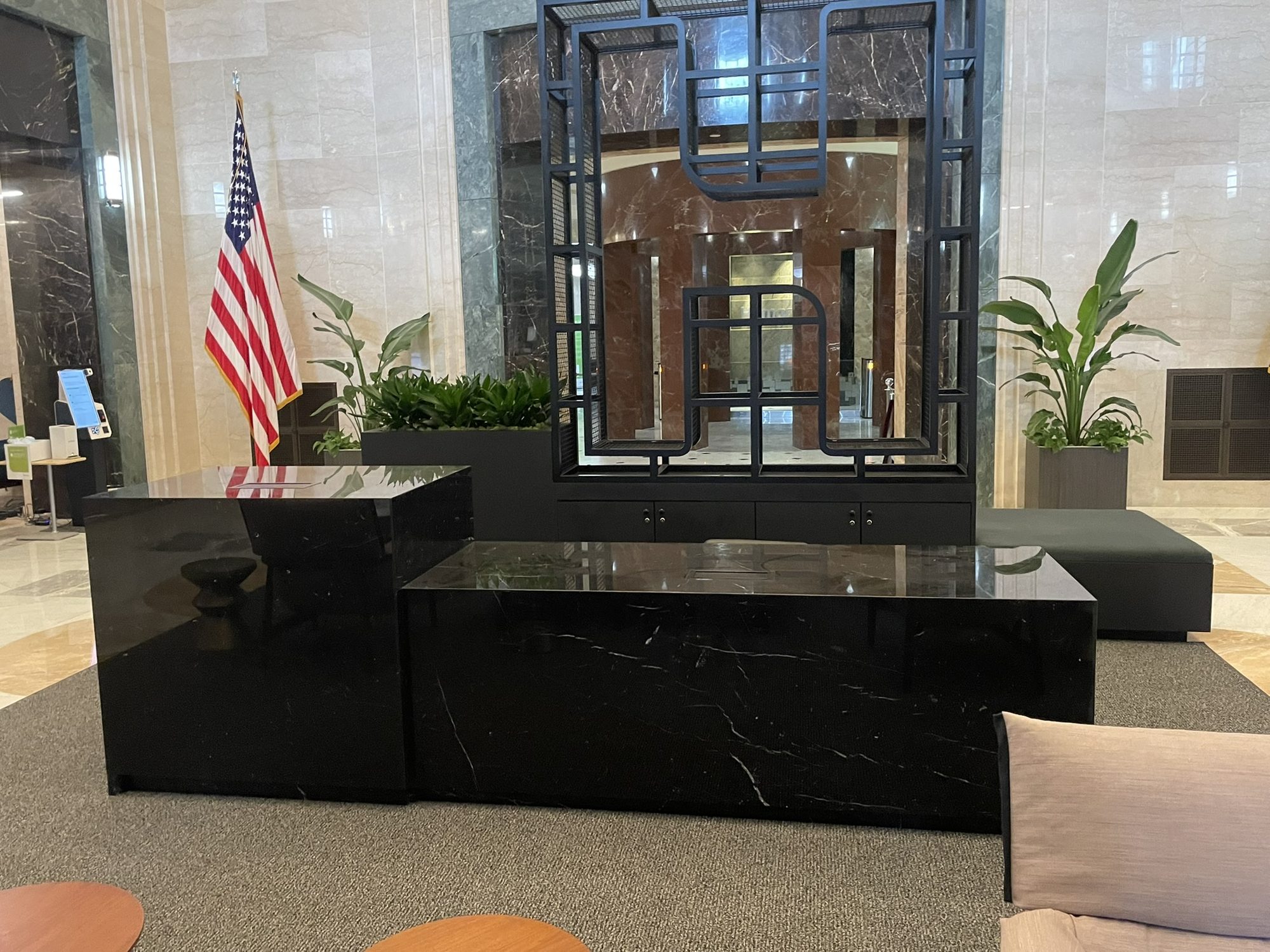 Black stone-clad lobby reception desk in a marble-lined building lobby